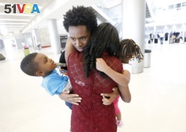 Olympic silver medalist Feyisa Lilesa, rear, of Ethiopia, hugs his wife Iftu Mulia, his daughter Soko, right, 5, and son Sora, left, 3, while picking up his family at Miami International Airport, Feb. 14, 2017.