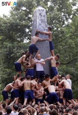 Plebes climb the grease-covered Herndon Monument on the United States Naval Academy campus in 2012.