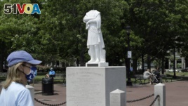 A passer-by walks near a damaged Christopher Columbus statue, Wednesday, June 10, 2020, in a waterfront park near the city's traditionally Italian North End neighborhood, in Boston.