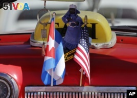 The stars and stripes and the Cuban national flag are placed together on the dashboard of a vintage American convertible in Havana, Cuba, Feb. 18, 2016.