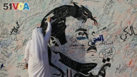 A man writes on a painting depicting Qatar's Emir Sheikh Tamim bin Hamad Al-Thani in Doha, Qatar, July 2, 2017. The artwork has attracted comments of support from residents amid a diplomatic crisis between Qatar and neighboring Arab countries.