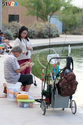 In this April, 30, 2020 photo, a couple sets up their lines to fish at Veterans Oasis Park in Chandler, Ariz. Fishing at community lakes has become a popular outdoor activity for people who have been locked up in their homes during the coronavirus pandemic. Many state fishing have continued to stock lakes during the outbreak. (AP Photo/John Marshall)