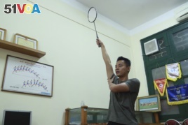 In this March 19, 2020, photo, a PE teacher demonstrates a badminton technique to his students during an online class at Nguyen Tat Thanh school in Hanoi, Vietnam. (AP Photo/Hau Dinh)