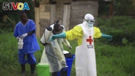 FILE - A health worker sprays disinfectant on his colleague after working at an Ebola treatment centre in Beni, Eastern Congo.