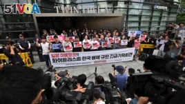 South Korean protestors hold signs saying 
