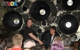 FILE - SpaceX CEO Elon Musk (L) shakes hands with Japanese billionaire Yusaku Maezawa during a press conference about being the first SpaceX private passenger to circle the moon aboard SpaceX's BFR launch vehicle, in Hawthorne, California on Sept. 17, 2018.