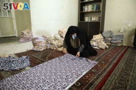 In a mosque in Tehran, Iran, a woman cuts bed sheets to make face masks for hospitals, April 5, 2020. (AP photo)
