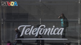 People are reflected in a glass sign of a Telefonica building in Madrid, Spain, May 13, 2017. The Spanish government said several companies including Telefonica had been targeted in ransomware cyberattack.