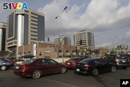 FILE- In this Tuesday, May. 26, 2015 file photo, cars queue in front of the Nigerian National Petroleum Corporation headquarters to buy fuel in Abuja, Nigeria. 