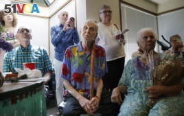 In this May 10, 2019, photo, Robert Fuller, center, leans on his walking stick and closes his eyes as he listens to music at a party in his honor in Seattle, Washington. (AP Photo/Elaine Thompson)
