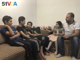 In this Sunday, Sept. 1, 2019 photo, Syrian refugee Zahir Hamshari sits with his children in his rented apartment in east Amman, Jordan. Seven years after fleeing the civil war in his homeland, Hamshari's life is filled with questions and doubts. (AP)