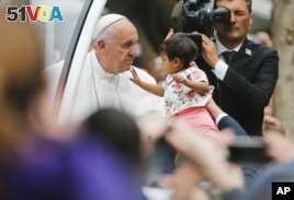 An unidentified child, carried from the crowd, touches Pope Francis' face as he heads to celebrate Sunday Mass on the Benjamin Franklin Parkway in Philadelphia, Sept. 27, 2015.