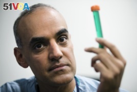 Surgeon Dr. Sunil Singhal poses for a photograph with a vial of fluorescent dye