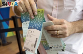 FILE - In this June 20, 2016, file photo, a man handles the Olympic tickets he just purchased at a shopping mall in Rio de Janeiro, Brazil. Tokyo Olympic organizers launched their ticket website on Thursday, April 18, 2019.