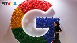 In this Monday, Nov. 5, 2018 file photo, a woman walks past the logo for Google at the China International Import Expo in Shanghai. (AP Photo/Ng Han Guan, File)