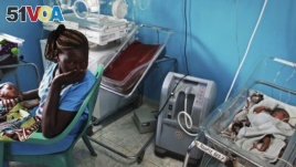 FILE - A woman holds her newborn baby in a nursery, while a newborn nearby is attached to a ventilator at Juba Teaching Hospital in Juba, April 3, 2013. South Sudan has one of the highest maternal mortality rates in the world.