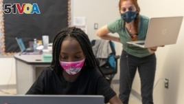 In this Tuesday, Sept. 29, 2020, photo English Language Arts teacher Rebecca Ain, right, helps a student in her class at The Social Justice Public Charter School, in Washington. (AP Photo/Jacquelyn Martin)