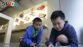 Apple Camp students Brandon Wong, 9, left, and Matthew Choy, 12, learn to program robots using the Sphero SPRK+ with the Lightning Lab application during a Coding Games and Programming Robots session in San Francisco, Wednesday, July 27, 2016. (AP Photo/J