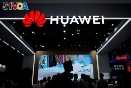 FILE - People walk past a sign board of Huawei at CES (Consumer Electronics Show) Asia 2018 in Shanghai, China, June 14, 2018.