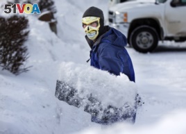 In Maine with the temperature at 3 degrees Fahrenheit, this man shovels snow wearing a face mask to guard against frostbite, January, 2014.