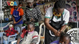 In this Sunday, May 3, 2020 file photo, Gettrueth Ambio, 12, center, Jane Mbone, 7, right, and Hamida Bashir, 3, left, have their hair styled in the shape of the new coronavirus, at the Mama Brayo Beauty Salon in Kibera.