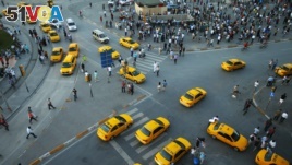 FILE - Yellow taxis pass people standing in silence during a protest at Taksim Square in Istanbul.