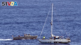 In this Oct. 25, 2017 photo, sailors from the USS Ashland approach a sailboat with two Honolulu women and their dogs aboard as they are rescued after being lost at sea for several months while trying to sail from Hawaii to Tahiti. 