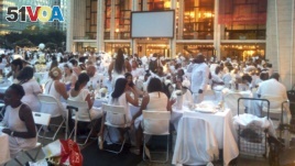 FILE - Guests wearing white clothing sit down to a pop-up dinner at New York's Lincoln Center, Tuesday, Aug. 22, 2017. The event, known as Diner en Blanc, French for Dinner in White, is an annual foodie tradition and began in Paris 29 years ago. (AP Photo)
