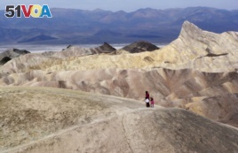 In this April 11, 2010 file photo, tourists walk along a ridge at Death Valley National Park, Calif. Preliminary data show that Death Valley set the world record for hottest month in July 2018.