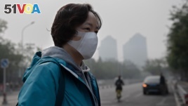 A woman wears a protective mask to fight bad air pollution in Beijing on October 22, 2018. (Photo by Nicolas ASFOURI / AFP)
