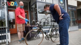 In this June 9, 2020 photo, Harvey Curtis, left, discusses repair plans with customer Jack Matheson outside Sidecountry Sports, a bike shop in Rockland, Maine.