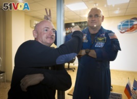 U.S. astronaut Scott Kelly, right, crew member of the mission to the International Space Station, ISS, poses through a safety glass with his brother, Mark Kelly, also an astronaut after a news conference in Russian leased Baikonur cosmodrome, Kazakhstan,