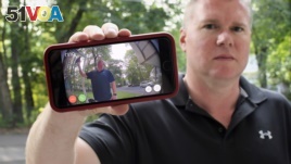 In this Tuesday, July 16, 2019, photo, Ernie Field holds up a live video of himself taken by a Ring doorbell camera at the front door at his home in Wolcott, Conn. (AP Photo/Jessica Hill)