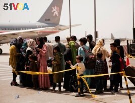 In this photo provided by the U.S. Marine Corps, civilians prepare to board a plane during an evacuation at Hamid Karzai International Airport, Kabul, Afghanistan, Wednesday, Aug. 18, 2021.
