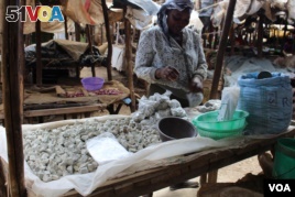 A woman sells odowa stones at a roadside market in Nairobi, Kenya (R. Ombuor/VOA).