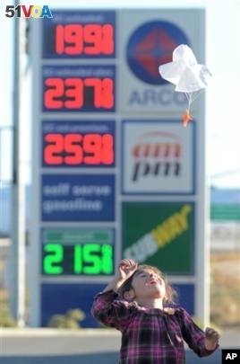 Joanna Alvarez plays with a toy parachute man at the Arco gas station parking lot where gasoline is posted at $1.99 a gallon in Oak Hills, Calif, on Wednesday, Feb., 24, 2016.  (David Pardo, Victor Valley Daily Press via AP)
