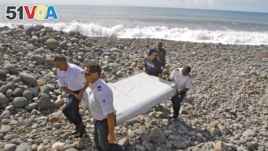 French police officers carry a piece of a plane wing found on Saint-Andre, Reunion Island, last month.