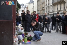 A man holds his head in his hands as he lays flowers in front of the Carillon cafe, in Paris, Nov. 14, 2015.