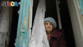 FILE - An elderly woman looks from her damaged flat after artillery shook Donetsk, eastern Ukraine, Feb. 3, 2017. 