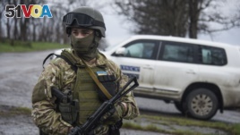 FILE - A Ukrainian soldier guards OSCE observers.