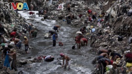 People search for scrap metal in polluted water at the bottom of one of the biggest trash dumps in the city, known as 