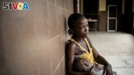 Rachel Sakie (16) and her daughter Isaatu (15 months) await for consultation at the Star of the Sun Health Center in the Monrovia township of West Point, Liberia, April 29, 2016.