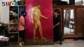 Argentine artist Marcelo Toledo (R) and his assistant Facundo Mineldin shift an art piece depicting Adam, which will be part of the 