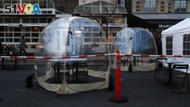 Pedestrians walk past temporary tents and structures erected outside of restaurants meant for outdoor dining in Washington, U.S. November 24, 2020. (REUTERS/Leah Millis)