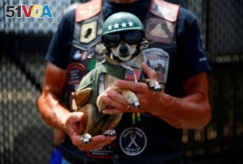 A man holds his dog, as participants gather in the parking lot of the Pentagon as thousands of military veterans and their supporters participate in the 31st annual Rolling Thunder motorcycle rally and Memorial Day weekend.