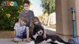 Christie Black, middle, with her two children, Angela and Luke, left, and the family dog Teddy, pose at their home, Tuesday, May 11, 2021, in Mesa, Ariz. (AP Photo/Ross D. Franklin) 