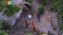 FILE - Members of an uncontacted Amazon Basin tribe and their dwellings are seen during a flight over the Brazilian state of Acre along the border with Peru in this May, 2008 photo distributed by FUNAI.