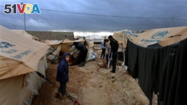 Syrian refugees help a wounded man fix his tent at Zaatari Syrian refugee camp, near the Syrian border in Mafraq, Jordan.