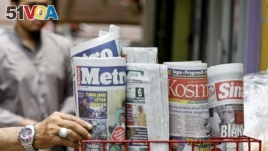 A man takes a copy of newspaper at a grocery shop in Shah Alam, Malaysia, Monday, March 26, 2018. Malaysia's government on Monday proposed new legislation to outlaw fake news with a 10-year jail term for offenders. (AP Photo/Sadiq Asyraf) 