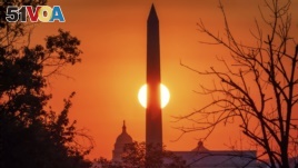 FILE - The sun rises behind the Washington Monument on the last day of summer in Washington, Monday, Sept. 21, 2020. A new report rates the U.S. and Britain as the largest exporters most active at enforcing rules meant to stop companies from paying bribes. (AP Photo/J. David Ake)